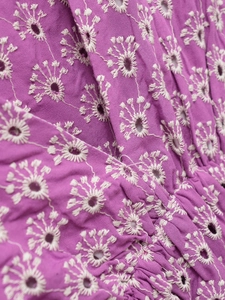 Details von violettem Stoff mit weißer Blumen-Ösenstickerei und aufwendigen Handarbeiten