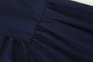 Detailed close-up of gathered navy fabric and fine stitching on the shirt sleeve