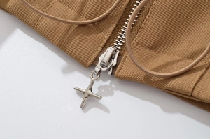 Macro detail of star-shaped metal zipper pull on khaki twill jacket with elastic cord
