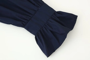 Detailed macro view of navy blue blouse showing pleated flare sleeves and ruffled cuffs