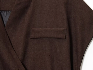 Close-up of brown textured vest featuring a horizontal welt pocket and neat black lining