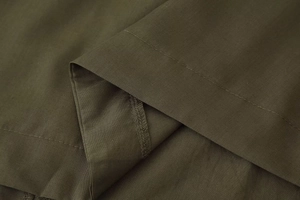 Detail of flat seam and overlock stitching on olive green V-neck dress fabric