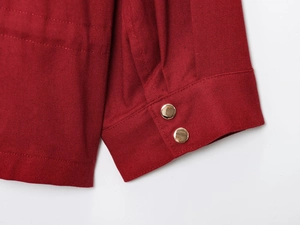 Detail of red cotton-linen jacket cuff with two elegant gold round metal buttons