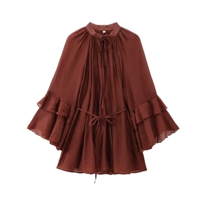 Macro shot of rust red pleated chiffon dress with ruffled bell sleeves and tie neck