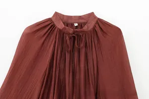 Close-up of pleated collar with tie detail and size S tag on brown women top