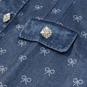 Detail of dark blue denim fabric with white bow patterns and a crystal button