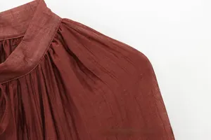 Detail of ruffle neck and vertical pleated texture on a brick red summer dress