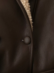 Detail of dark brown leather jacket with beige faux fur lining and stitched button