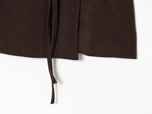 Macro detail of dark brown wide-leg trousers featuring adjustable drawstring and woven fabric