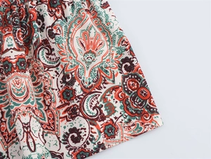 Détail du tissu à imprimé cachemire bohème avec motifs floraux orange et verts