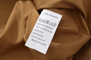 Close-up of garment care label showing 100% polyester fabric and washing instructions