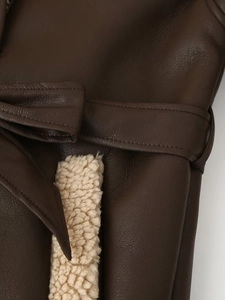 Detail of faux leather coat featuring a tie waist belt and plush shearling lining