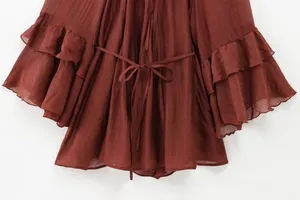 Detail of rust red chiffon dress featuring tiered ruffle sleeves and a matching waist tie