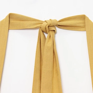 Gros plan du lien de cou licou jaune gingembre avec texture lin sur robe d'été