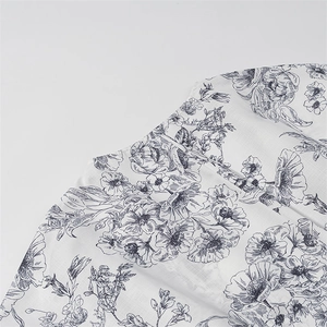 Macro detail of elegant blue floral print on lightweight white fabric with fine stitching