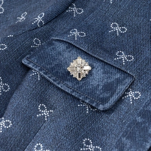 Detailed macro view of denim fabric with bow prints and a sparkling rhinestone button