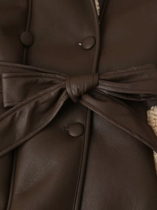 Detail of dark brown faux leather coat with bow tie waist belt and plush shearling lining