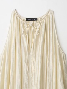 Close-up of cream sleeveless dress with pleated neckline and drawstring tie detail