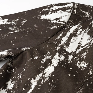 Dettaglio della giacca in twill marrone scuro con stampa tie-dye bianca e cuciture fini