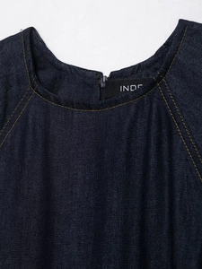 Detail of dark blue denim dress with round neck, invisible back zipper, and contrast stitching