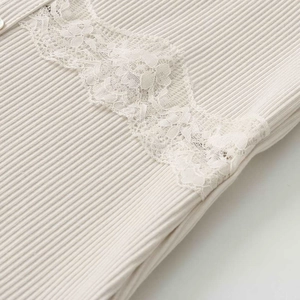 Détail de maille côtelée avec dentelle délicate et bouton blanc sur le haut beige clair