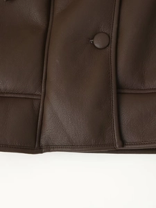 Macro shot of dark brown faux leather texture with neat stitching and covered button