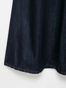 Detail of dark blue denim dress hem with contrast yellow stitching on heavy fabric