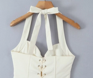 Detail of white halter corset top featuring adjustable bow tie and lace-up front design