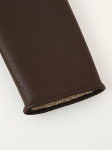Detailed macro view of dark brown leather sleeve with thick beige faux fur lining and stitching