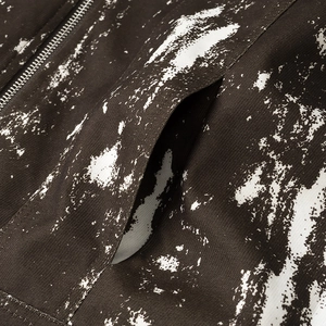 Dettaglio della cerniera metallica e texture bianca su giacca in tela marrone