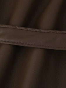 Macro view of stitching and waist belt detail on dark brown faux fur leather jacket