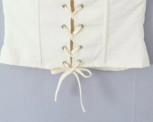 Detailed view of the off-white lace-up bodice featuring metal eyelets and a bow tie closure