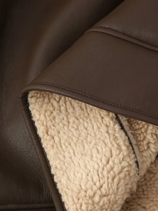 Detailed macro view of deep brown leather jacket with soft beige faux fur lining