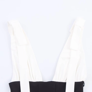 Detail of a deep V-neck black and white patchwork dress with textured fabric and wide straps