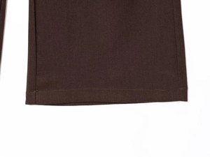 Detail of dark brown trousers featuring reinforced double-stitched seams and heavy cotton fabric