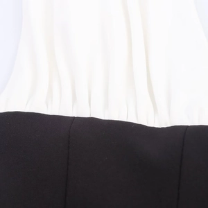 Macro detail of white pleated fabric stitched to black plain material on a stylish dress
