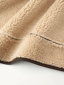 Detail view showing stitching of beige faux shearling and brown faux leather coat hemline
