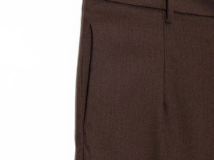 Detailed close-up of brown trousers showing waist loops, pockets, and premium fabric texture