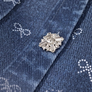 Detail of rhinestone floral button on a dark blue denim dress with white bow prints