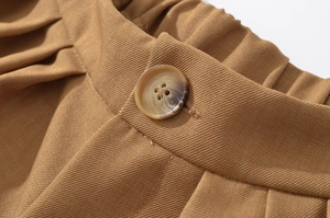 Macro detail of khaki twill jacket with marbled button and tailored pleat accents