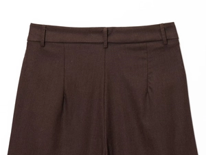 Detail of dark brown trousers waist featuring belt loops and pleated textured fabric