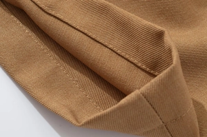 Detailed close-up of double-stitched seams on dark khaki twill cotton jacket hem