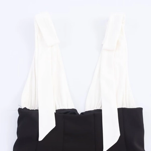 Detail of contrast color dress showing white V-neck bow straps and black waist design
