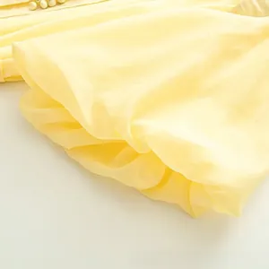 Vue détaillée d'une robe en mousseline jaune clair avec des volants et des perles