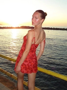 Detail of red floral chiffon mini dress with shoulder tie straps at seaside sunset