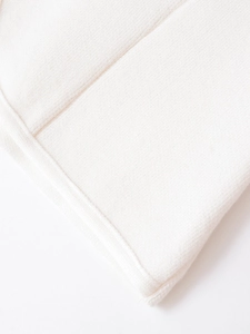 Detailed close-up of white knitted fabric texture with high-quality finished edge stitching
