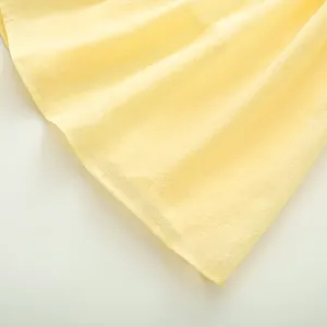 Détail du tissu de robe d'été jaune clair avec texture froissée et coutures de l'ourlet nettes