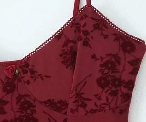 Detail of burgundy burnout velvet dress featuring a 3D rose and ruffle hemline