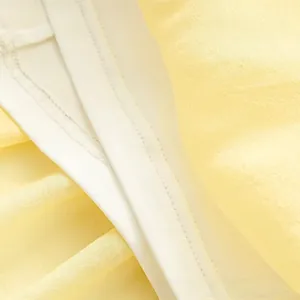 Détail du tissu en mousseline jaune pâle montrant le tissage fin et les coutures précises