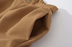 Close-up of brown twill cotton jacket with elastic waist and natural wood texture button
